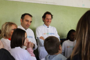 Foto di Stefano Lo Russo e John Elkann che parlano con dei bambini.