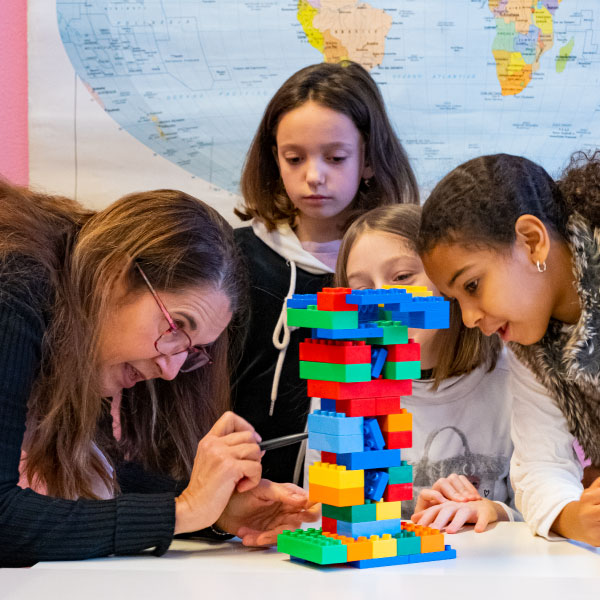 Foto di una maestra che spiega ai bambini attraverso l'uso di mattoncini LEGO Duplo.