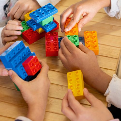 Foto di mani di bambini che giocano con dei blocchi Duplo